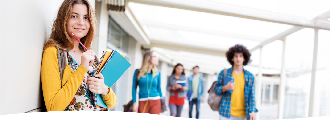 Jugendliches Mädchen steht im Vordergrund im Gang einer Schule
