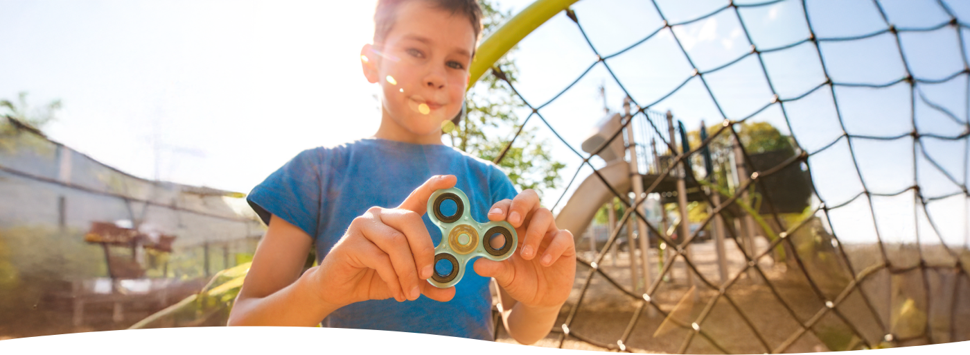 Spielender Bub auf einem Spielplatz vor einer Rutsche